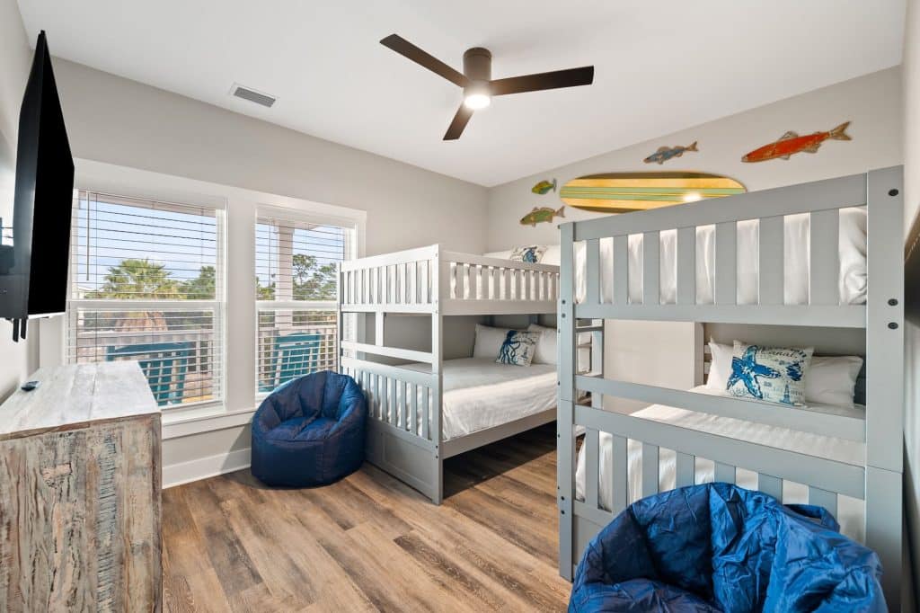 coastal designed kids bedroom with two sets of bunk beds with beachy white and blue furniture and accessories designed and decorated by Shore House Furniture in Panama City Beach Florida