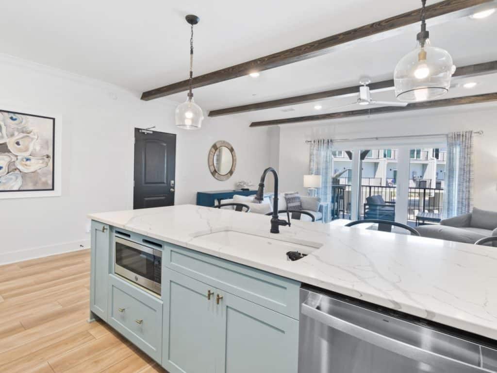 coastal designed sitting area and open kitchen with beachy white and blue accessories designed and decorated by Shore House Furniture in Panama City Beach Florida