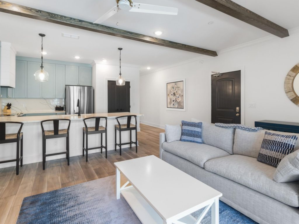 coastal designed sitting area and open kitchen with beachy white and dark blue accessories designed and decorated by Shore House Furniture in Panama City Beach Florida