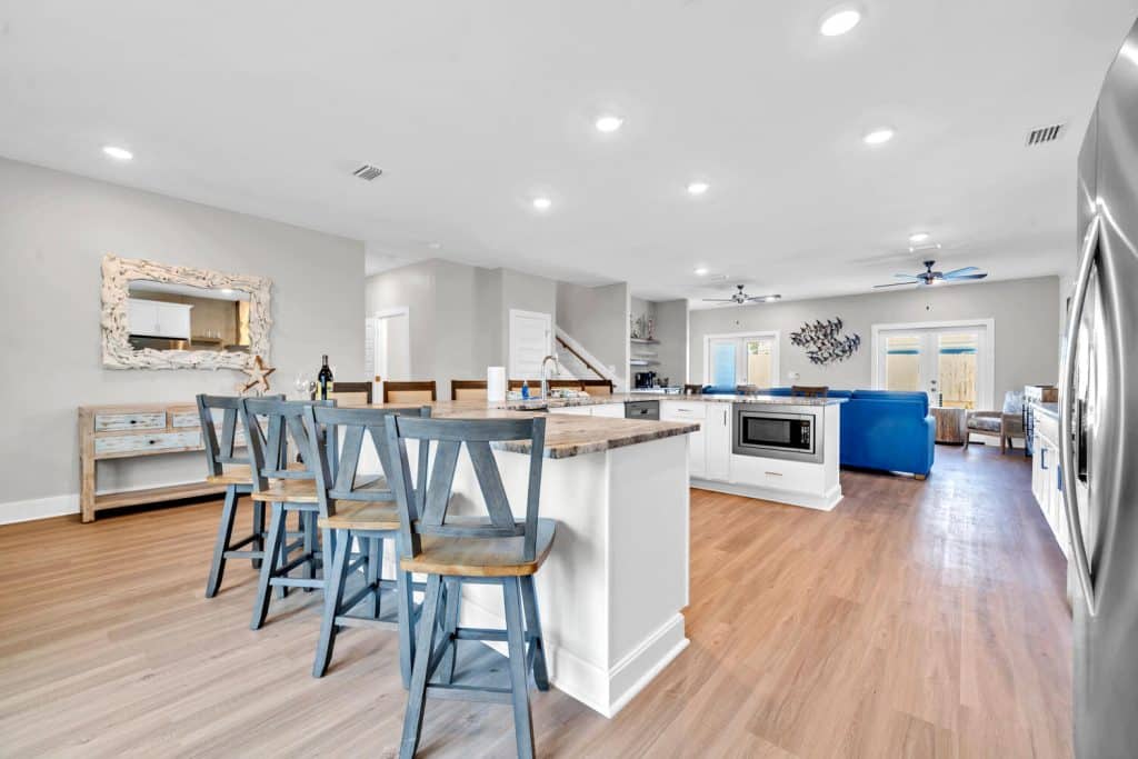 coastal designed open floor plan kitchen and breakfast bar with beachy white and dark blue accessories designed and decorated by Shore House Furniture in Panama City Beach Florida
