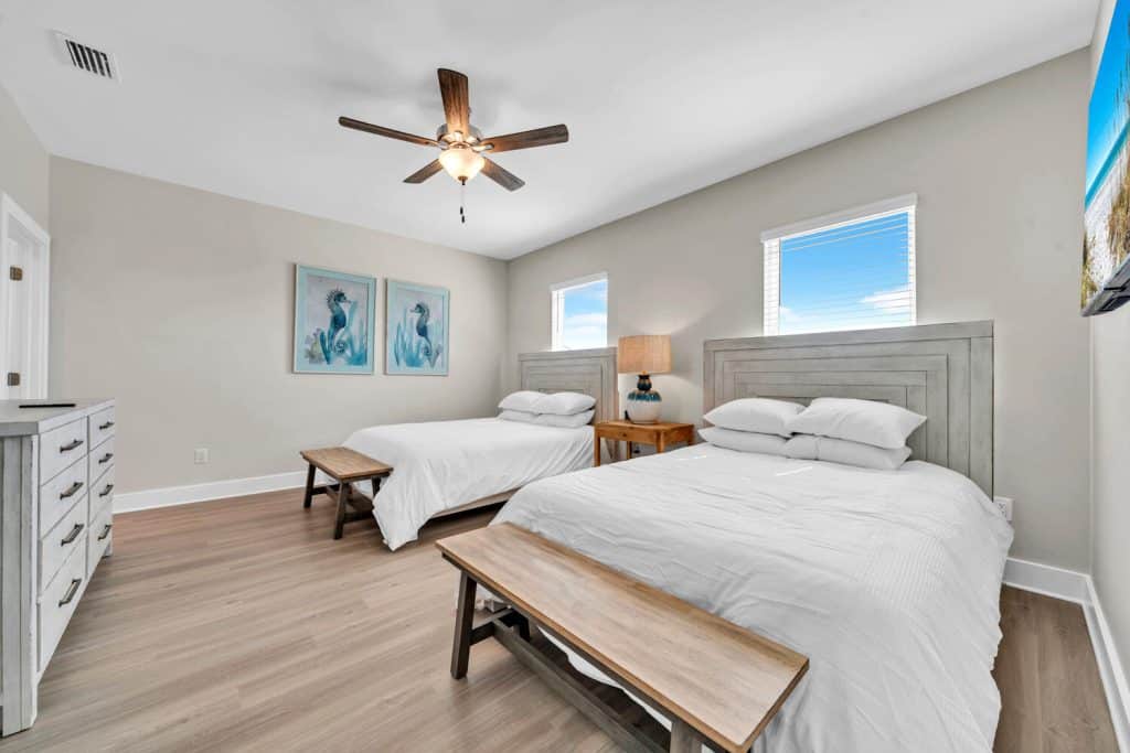 coastal designed guest bedroom with two queen beds and a bunk bed with beachy white accessories designed and decorated by Shore House Furniture in Panama City Beach Florida