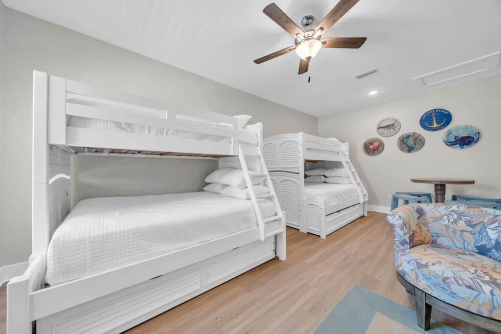 coastal designed guest bedroom with two sets of bunk bed and beachy white and blue accessories designed and decorated by Shore House Furniture in Panama City Beach Florida