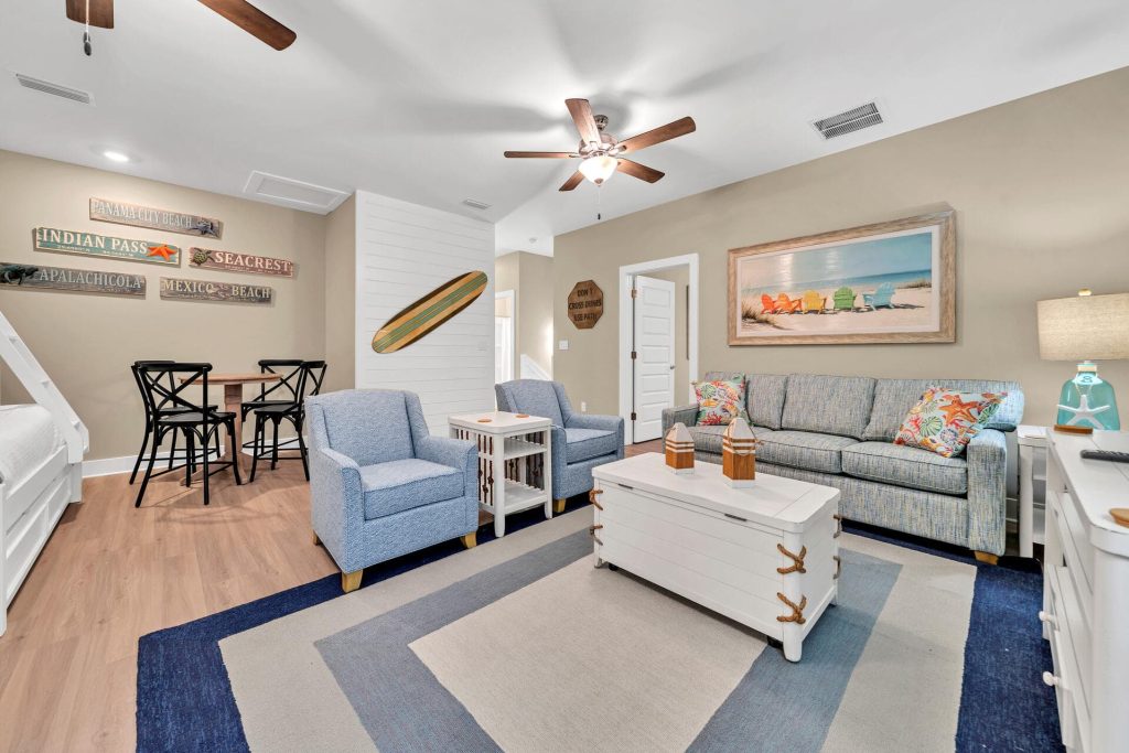 coastal designed guest bedroom with 2 sets of bunkbeds couches and chairs with beachy white and teal accessories designed and decorated by Shore House Furniture in Panama City Beach Florida