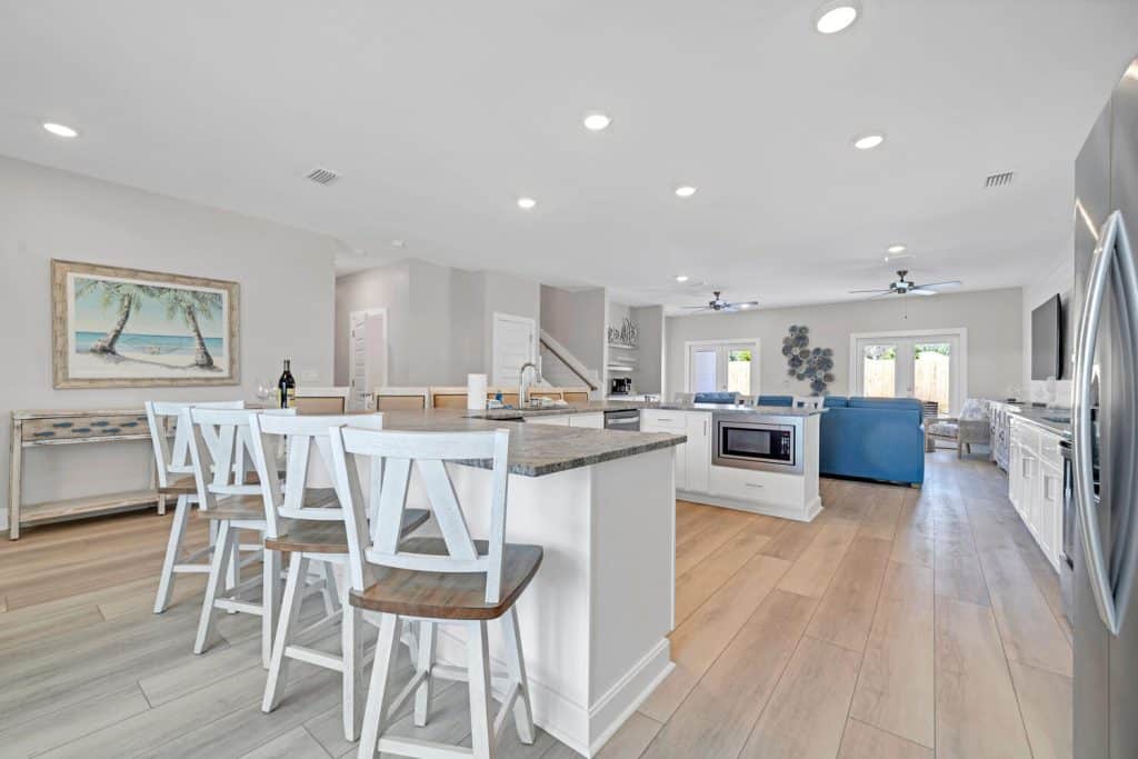 coastal designed open floor plan kitchen and breakfast bar with beachy white and dark blue accessories designed and decorated by Shore House Furniture in Panama City Beach Florida