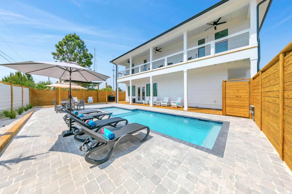 coastal designed outdoor pool and patio area with beachy accessories designed and decorated by Shore House Furniture in Panama City Beach Florida