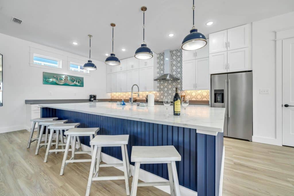 coastal designed dining and kitchen area open floor plan with beachy white and blues accessories designed and decorated by Shore House Furniture in Panama City Beach Florida