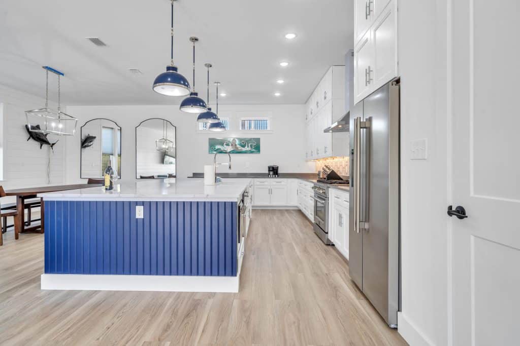 coastal designed living dining and kitchen area open floor plan with beachy white and blues accessories designed and decorated by Shore House Furniture in Panama City Beach Florida